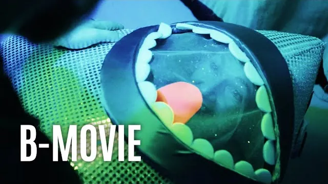Still from B-Movie: a homemade monster prop under neon light